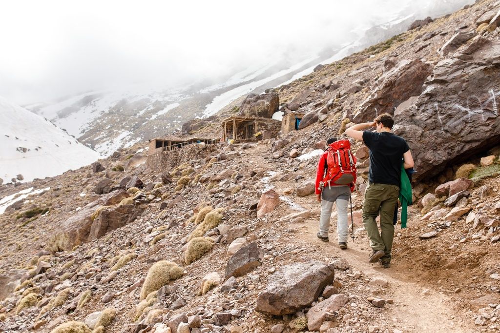 Two trekkers climbing up to Imlil Base Camp in Morocco.