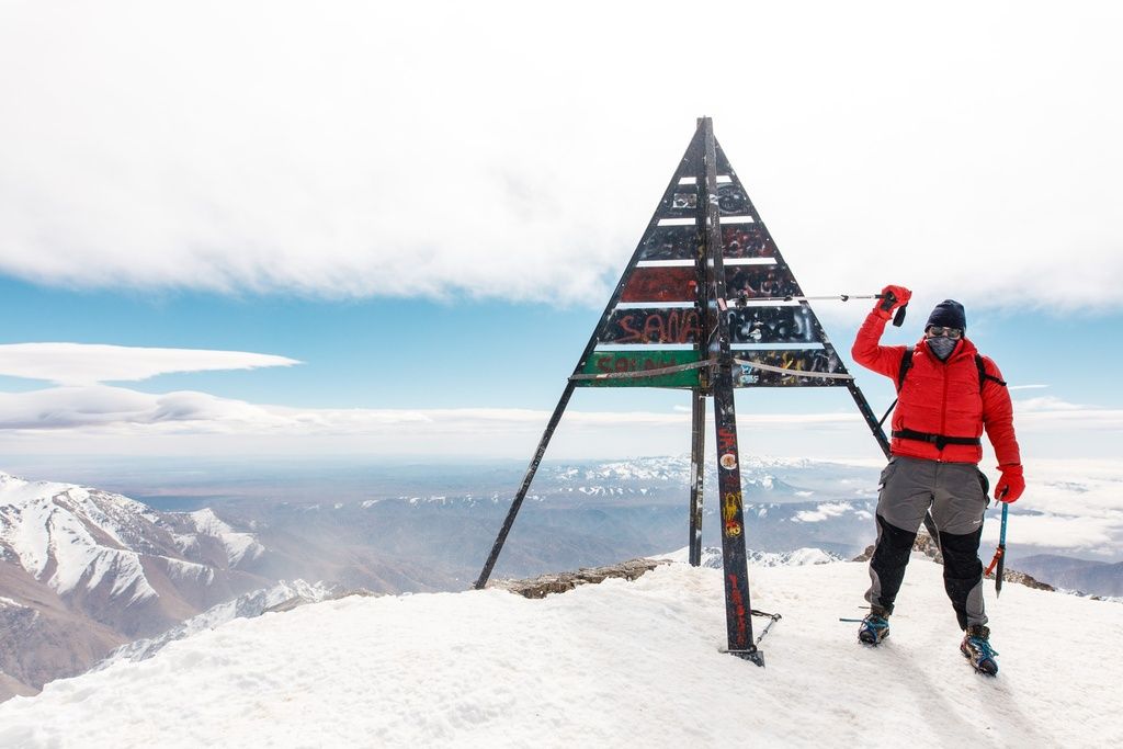 A hiker standing at the summit of Mount Toubkal in Morocco