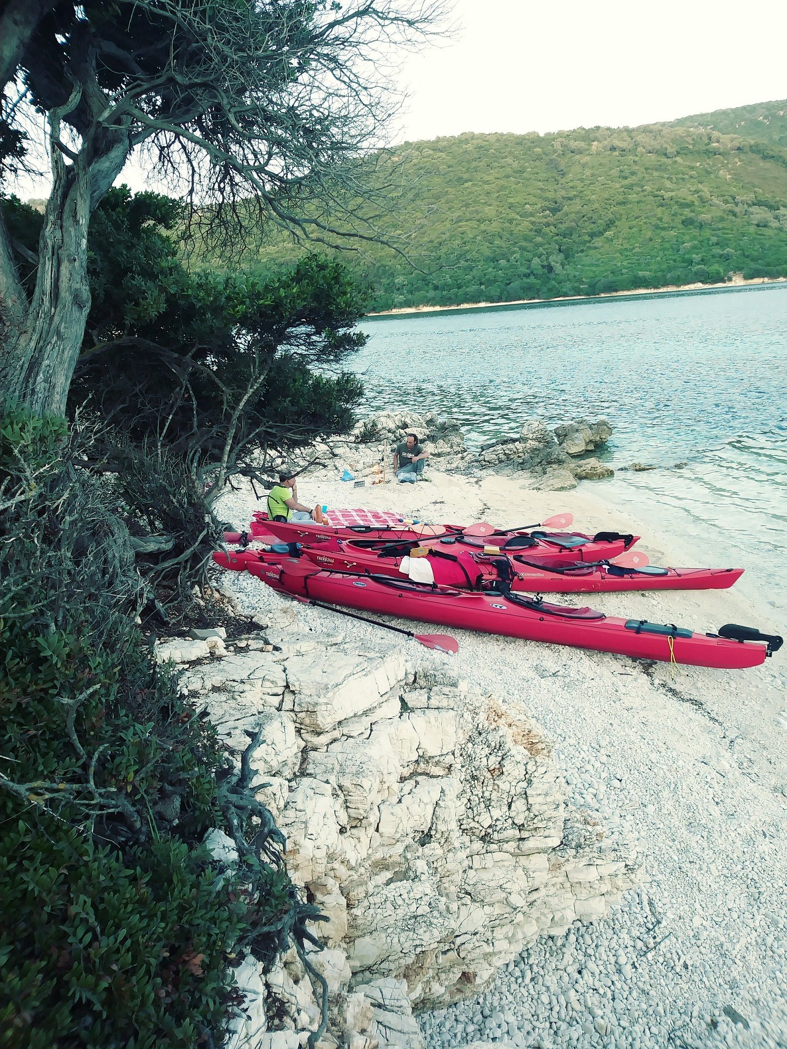 Two men with their kayaks on a beach of Thillia Island, Greece