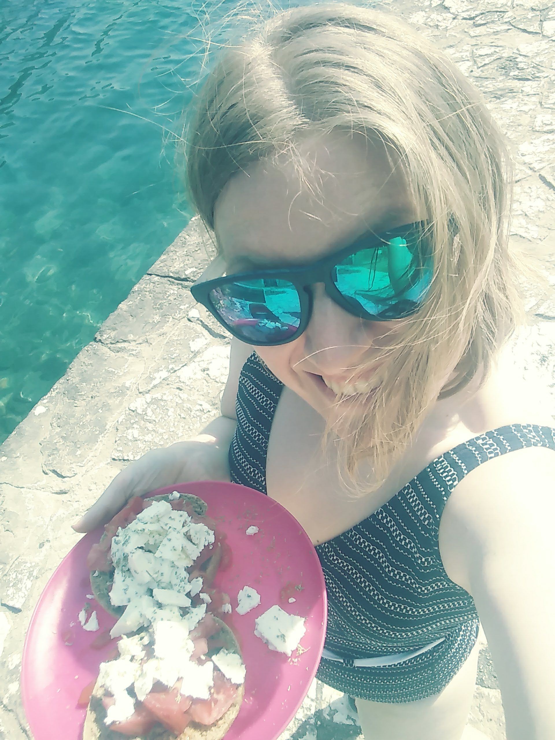 A woman takes a selfie with her lunch in Greece.
