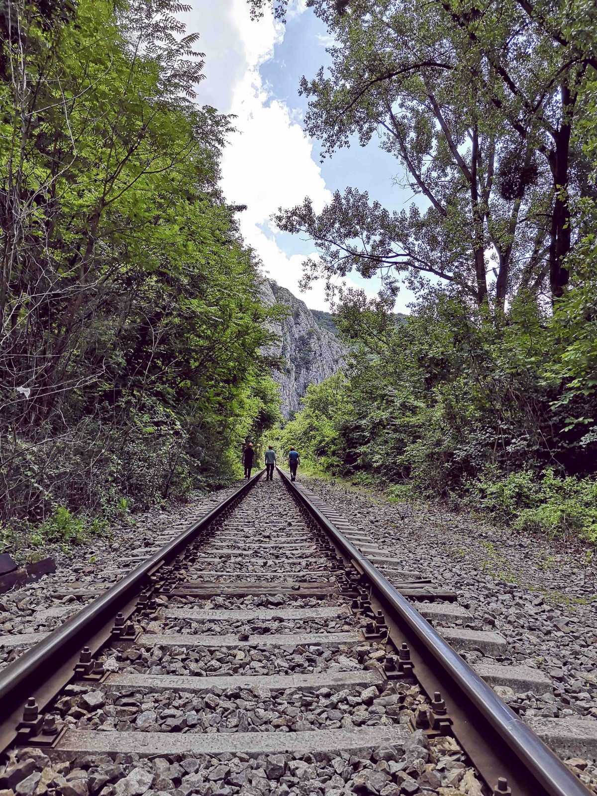 Three people walking along train tracks in the Western Carpathians.