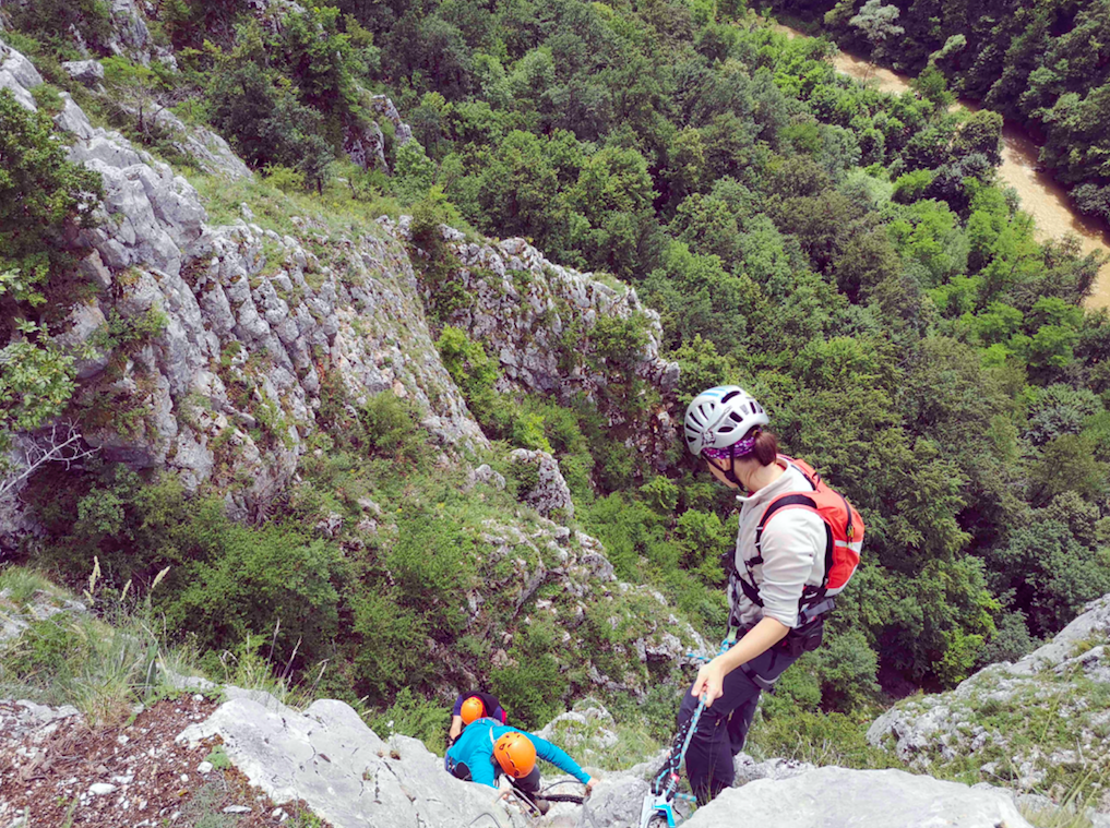 Hikers wearing helmets and harnesses climbing a via ferrata in the Western Carpathians.