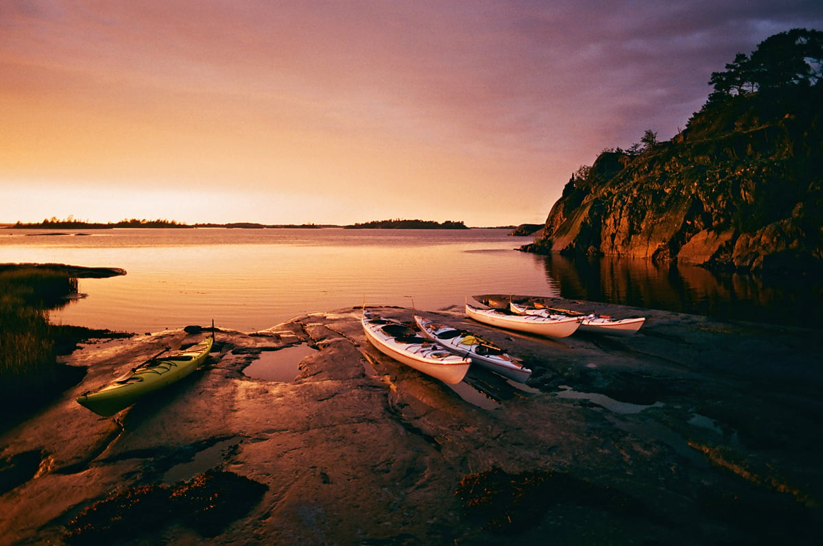 Kayaks pulled ashore on the Saint Anna Archipelago at sunset.