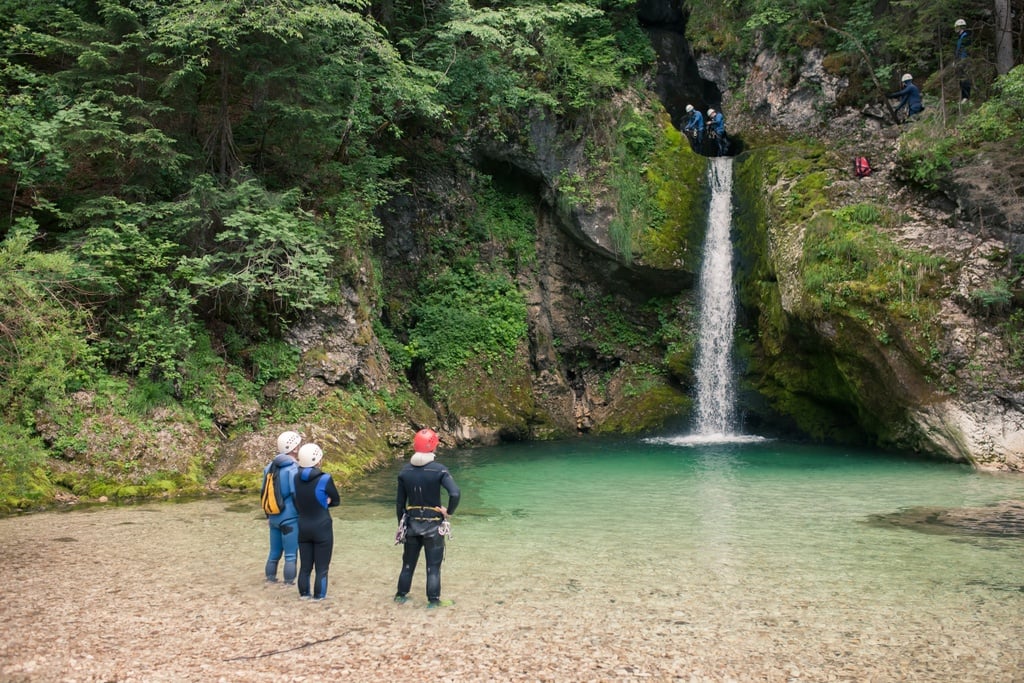 A canyoning group get ready to rappel down a waterfall in the Grmečica canyon, Slovenia