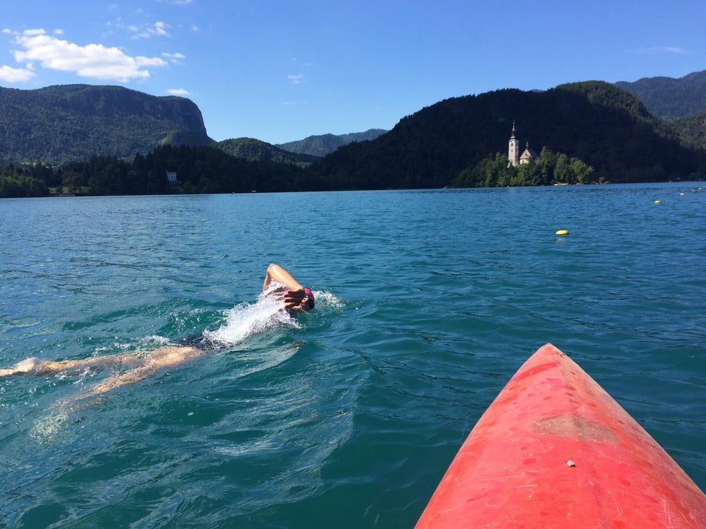 A swimmer in Lake Bled, Slovenia, with a kayak in the foreground.