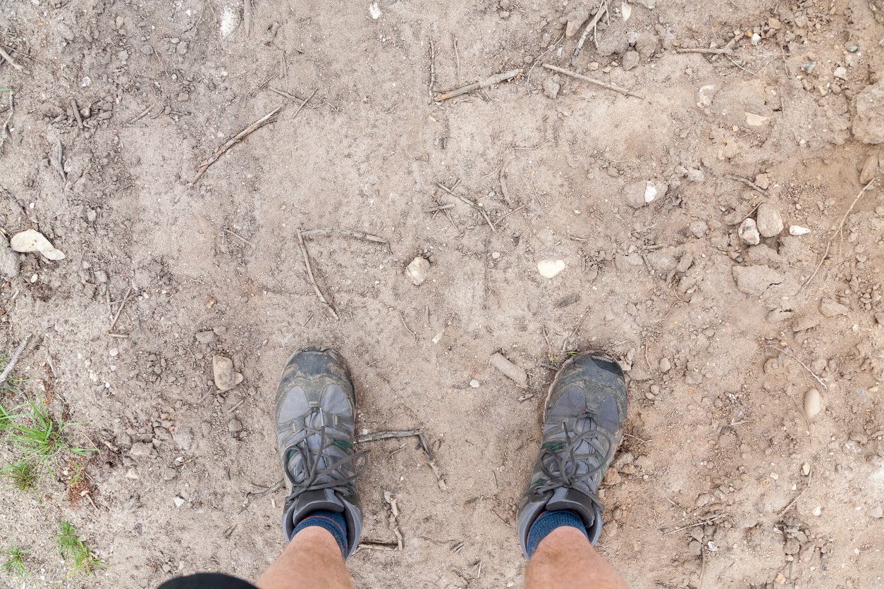 A pair of hiking shoes on a dusty floor.