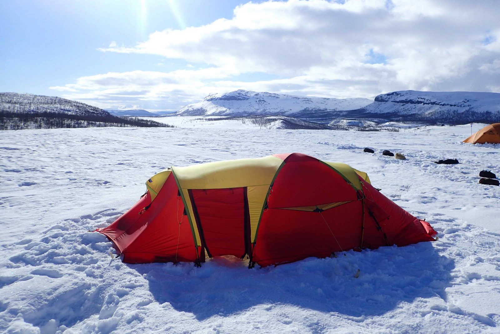A tent in the Arctic circle, surrounded by snow and mountains.