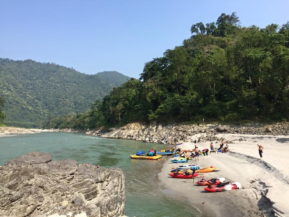 A group of rafters prepare to set sail, surrounded by lush jungle and beautiful water.