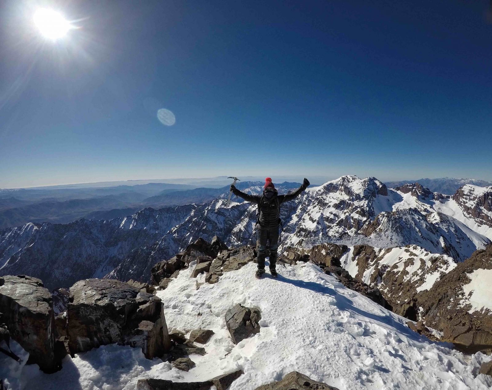 A hiker cheering on the summit of Mount Toubkal.