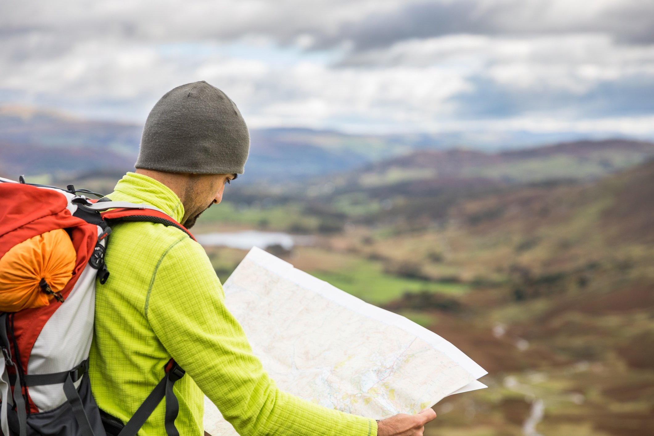 A hiker map reading, with hills in the background.