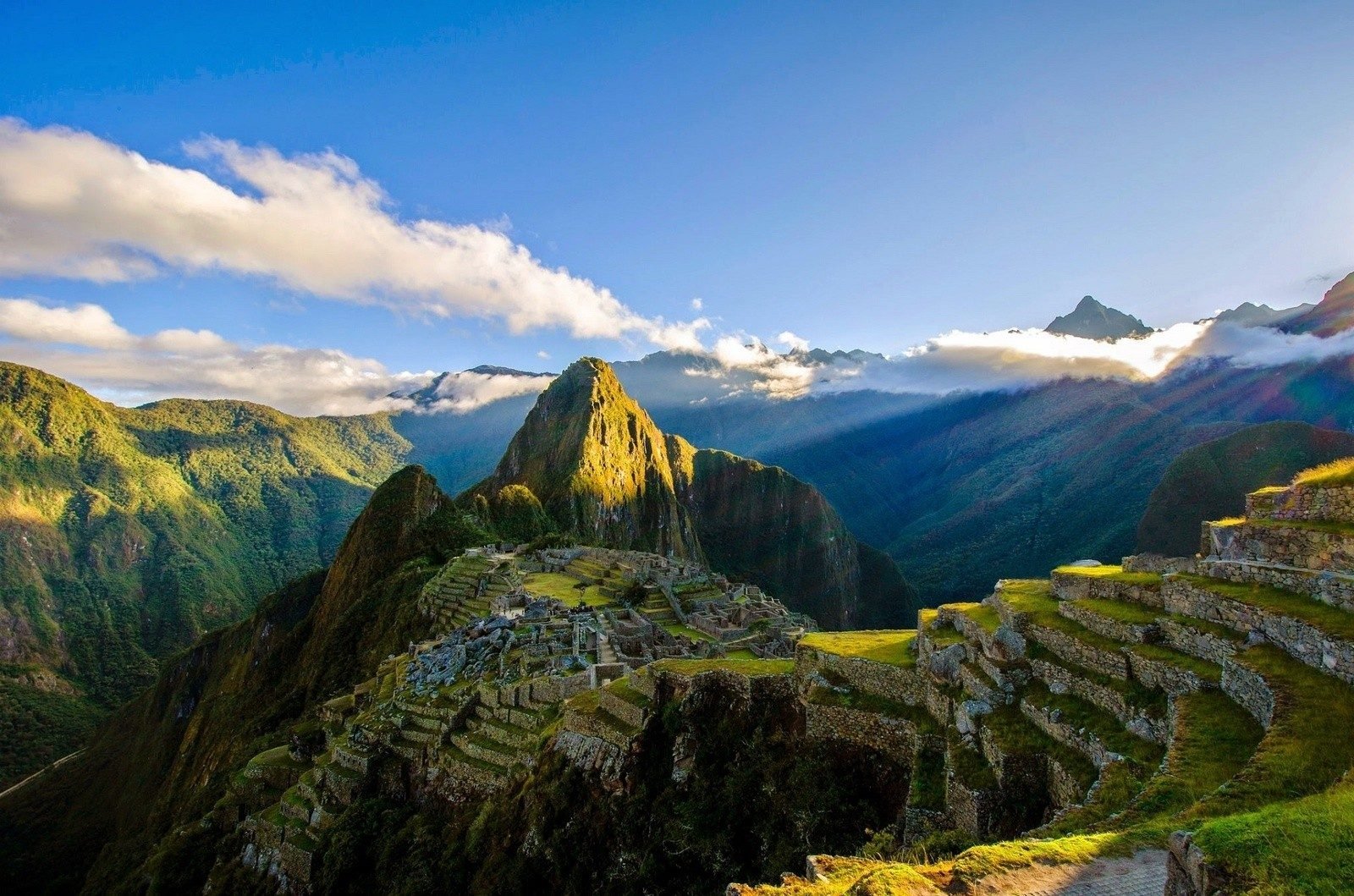 Machu Picchu, surrounded by green mountains.
