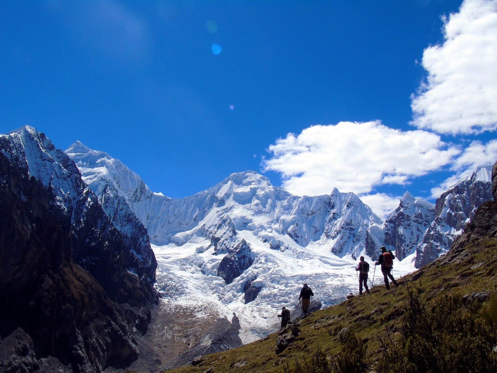 Hikers in Peru, snow capped mountain peaks in the background.