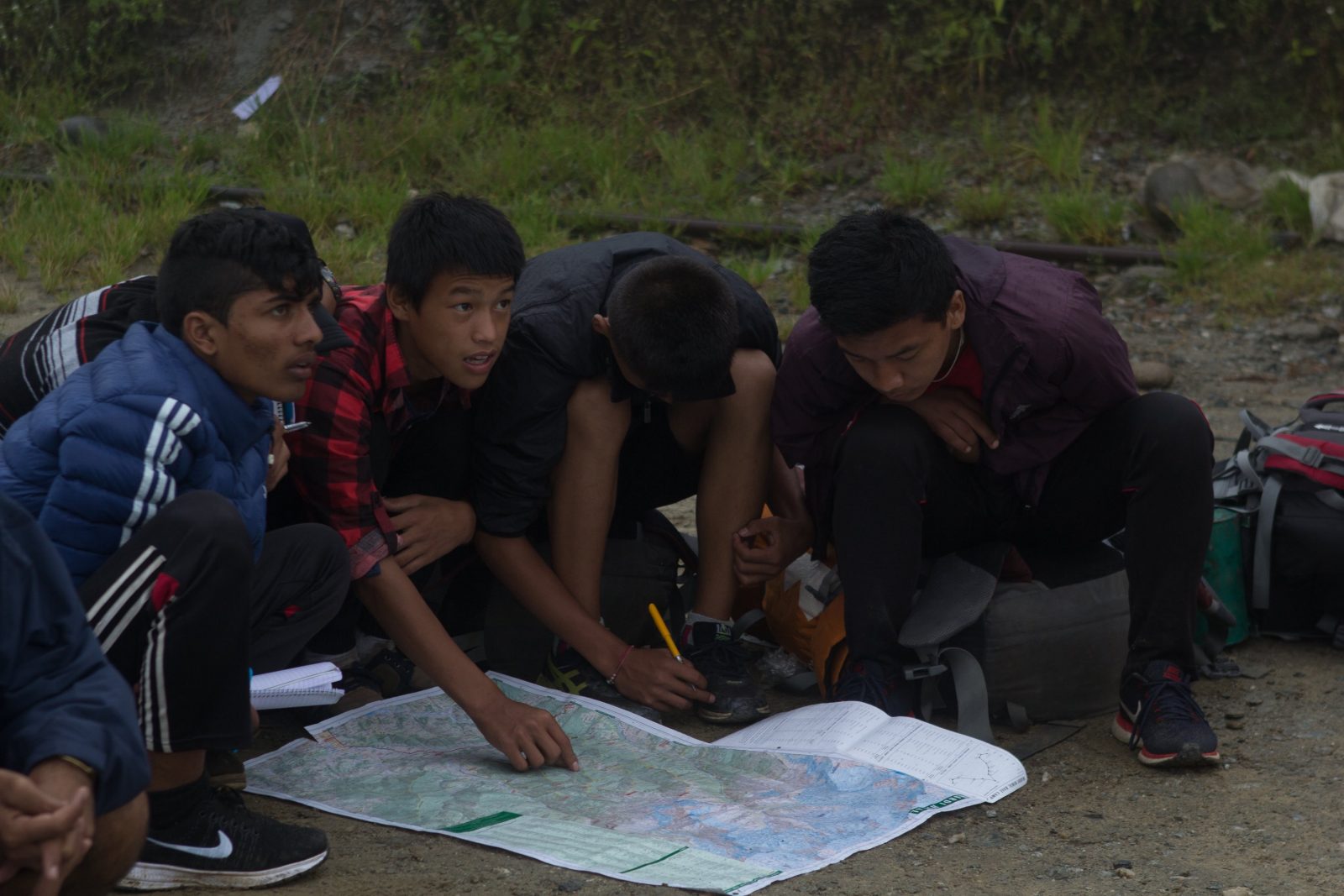 A group of Nepalese boys pore over a map in the mountains.