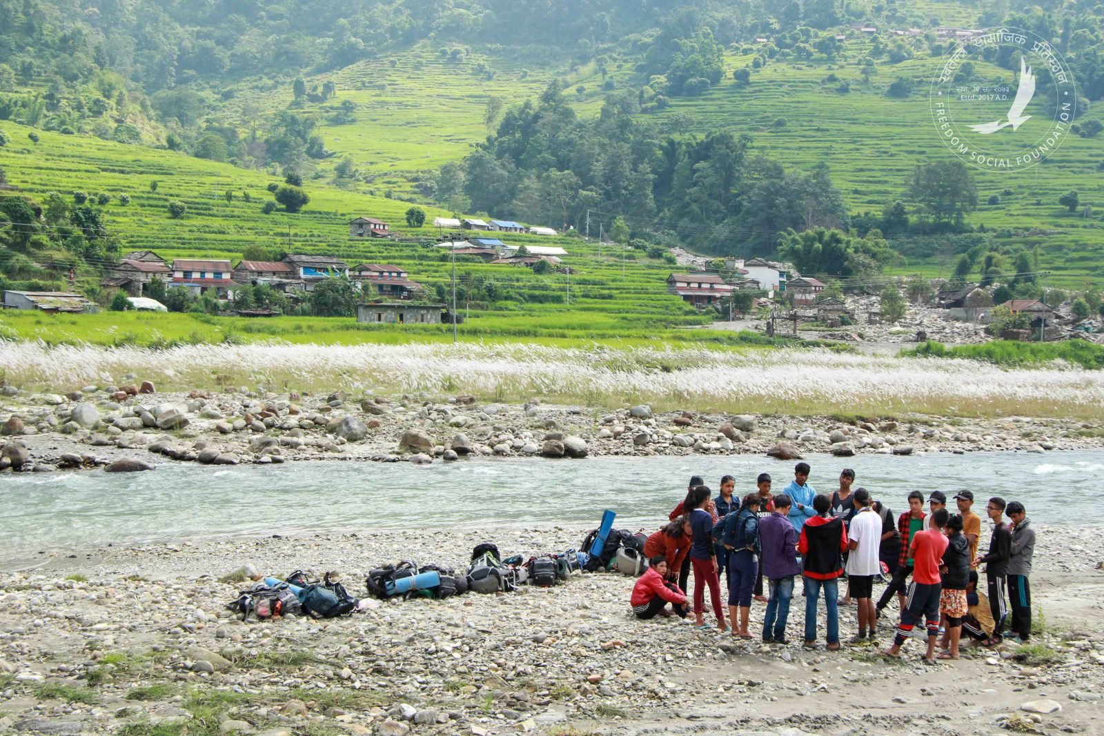 A youth group listens to a safety talk before crossing a river in Nepal.