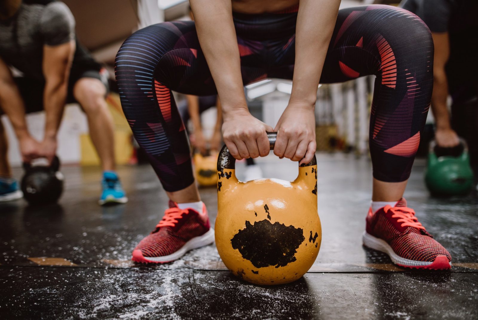 Close up of a kettle bell, with someone squatting behind it