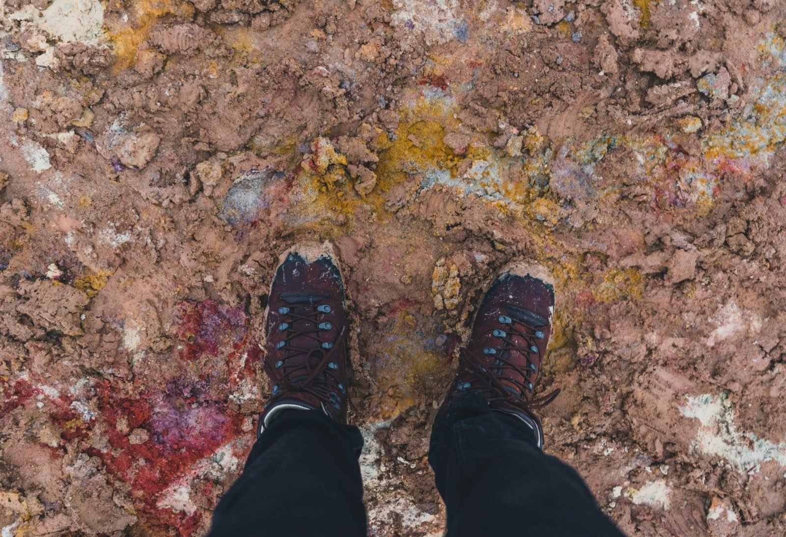 worn-in hiking boots, surrounded by and covered in volcanic mud