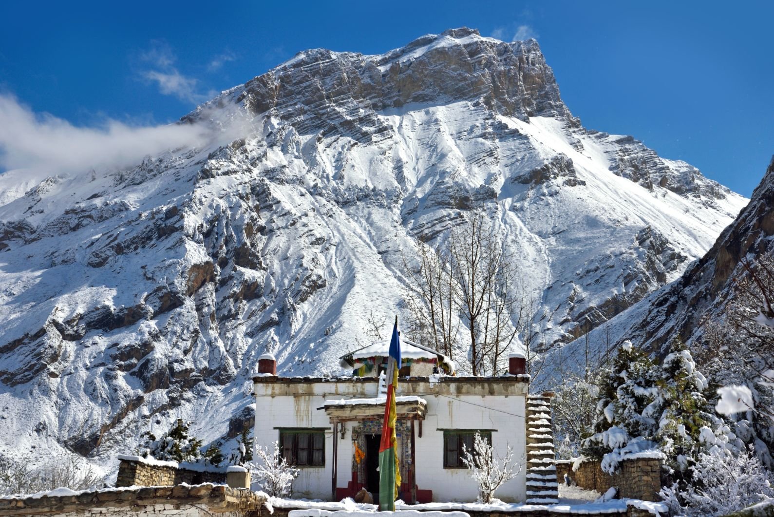 Buddhist Prayer Flags and a snow stupa along the Annapurna circuit.