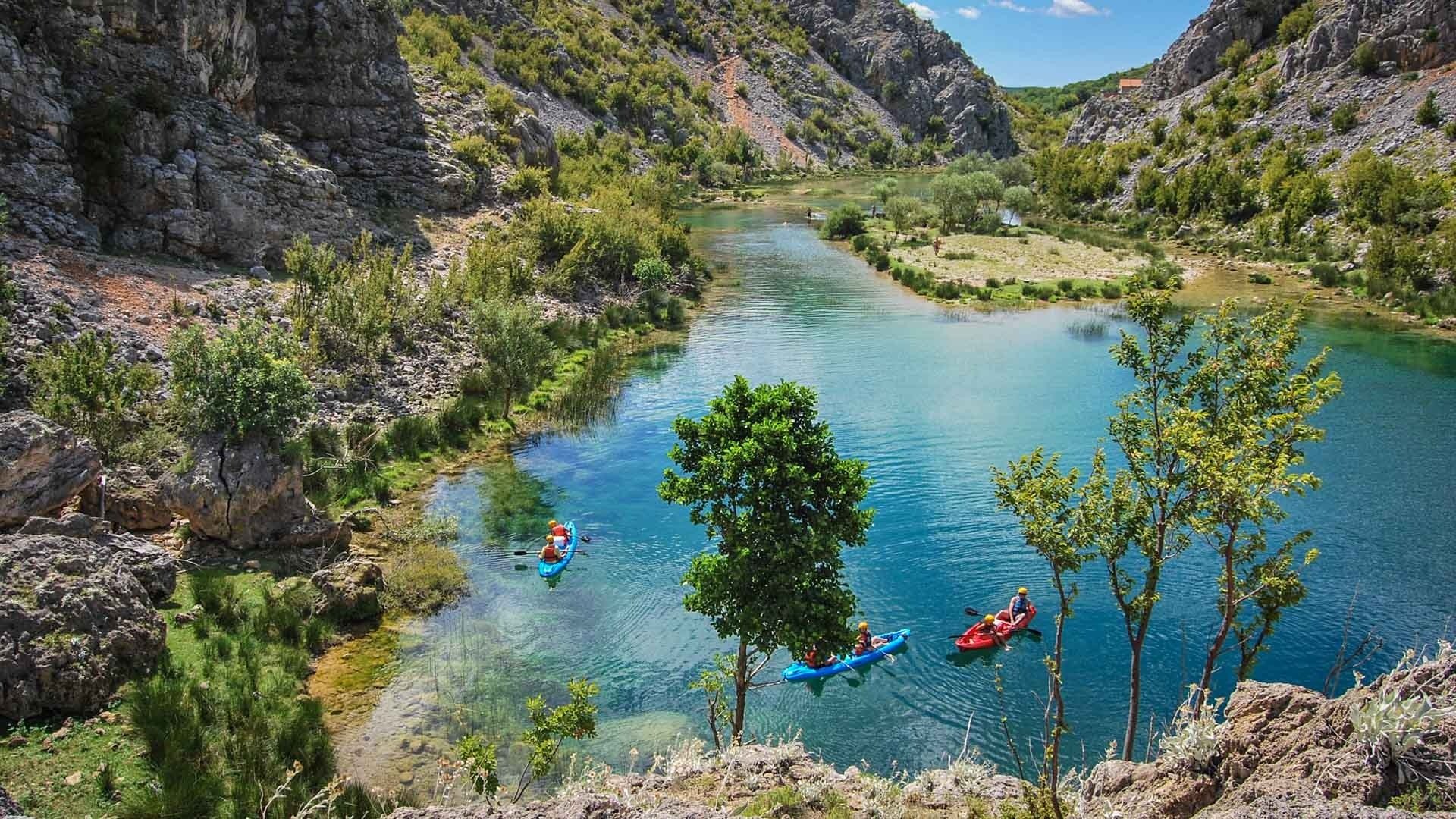 Kayakers in a clear turquoise river in Croatia's Dalmatia Region.
