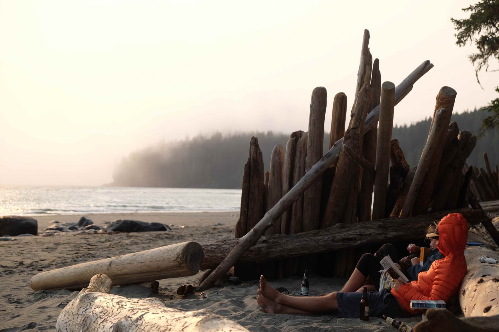 A couple reading on a beach in Vancouver Island, Canada, on a misty morning.