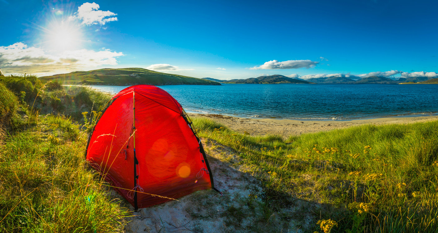 Bright red dome tent pitched on idyllic sand dunes