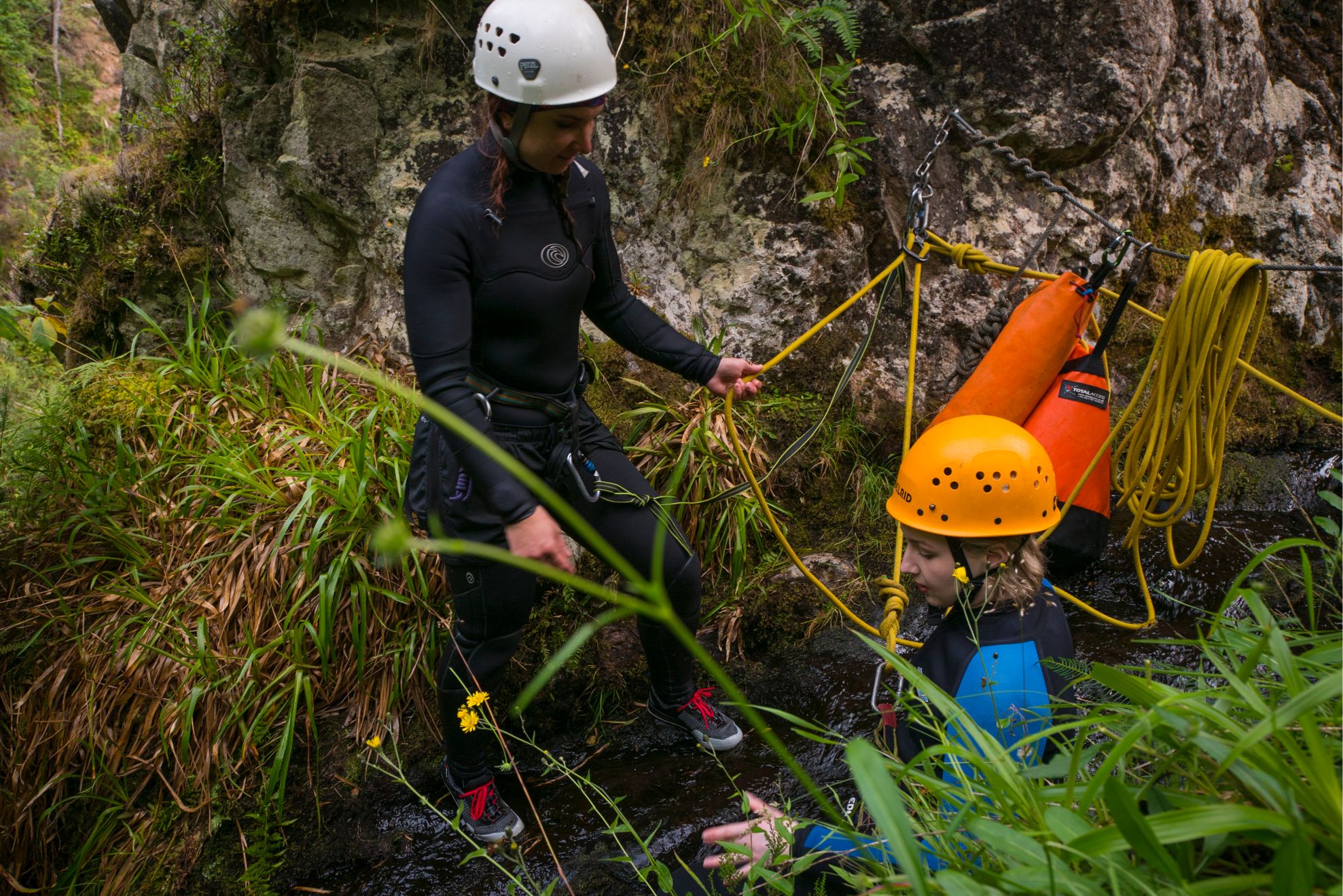Two people out canyoning, who are roped together.