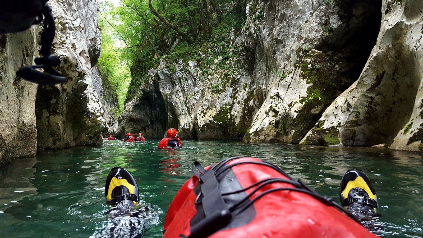 A group canyoning in a river, from the close-up perspective of one of the canyoners.