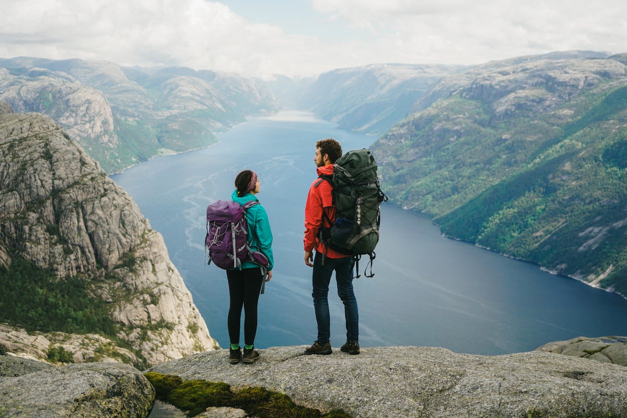 Man and woman hiking near Preikstolen and looking at Lysefjorden