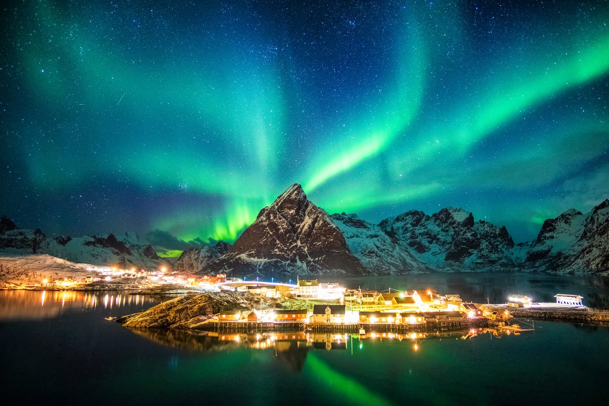 Aurora borealis over mountains in fishing village at Sakrisoy, Lofoten Islands, Norway