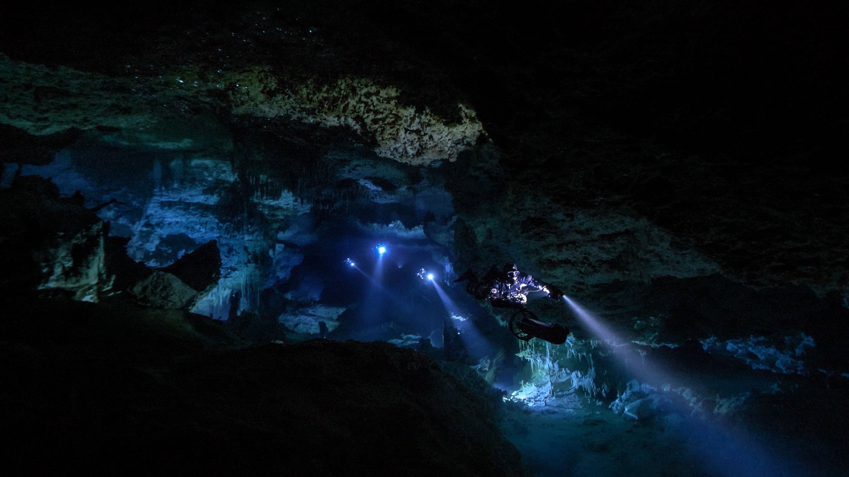 A diver, swimming through a dark cave.