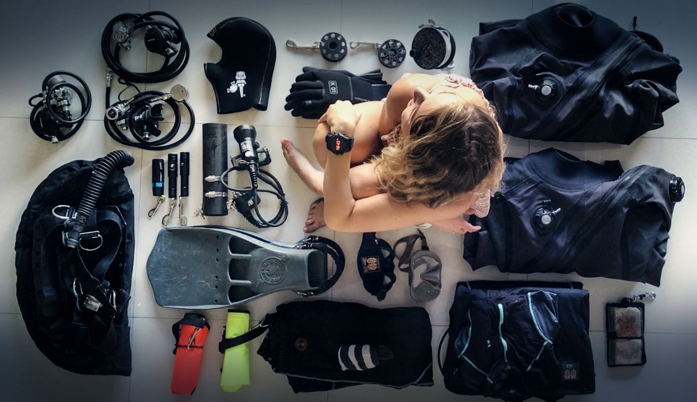 A woman in her swimming costume, surrounded by diving equipment.