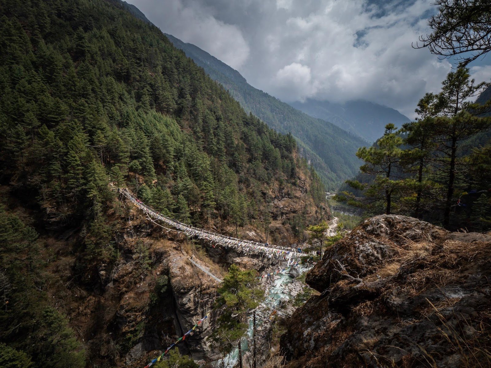A suspension bridge in the Nepal Himalayas, stretching over a glacial river.