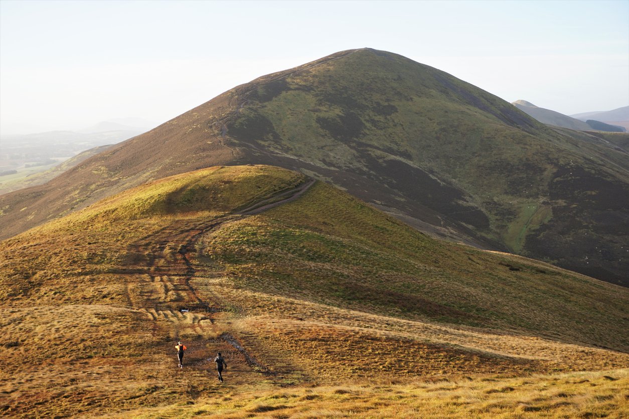 Two hikers make their way from the top of Turnhouse Hill towards Carnethy Hill in the Pentlands.