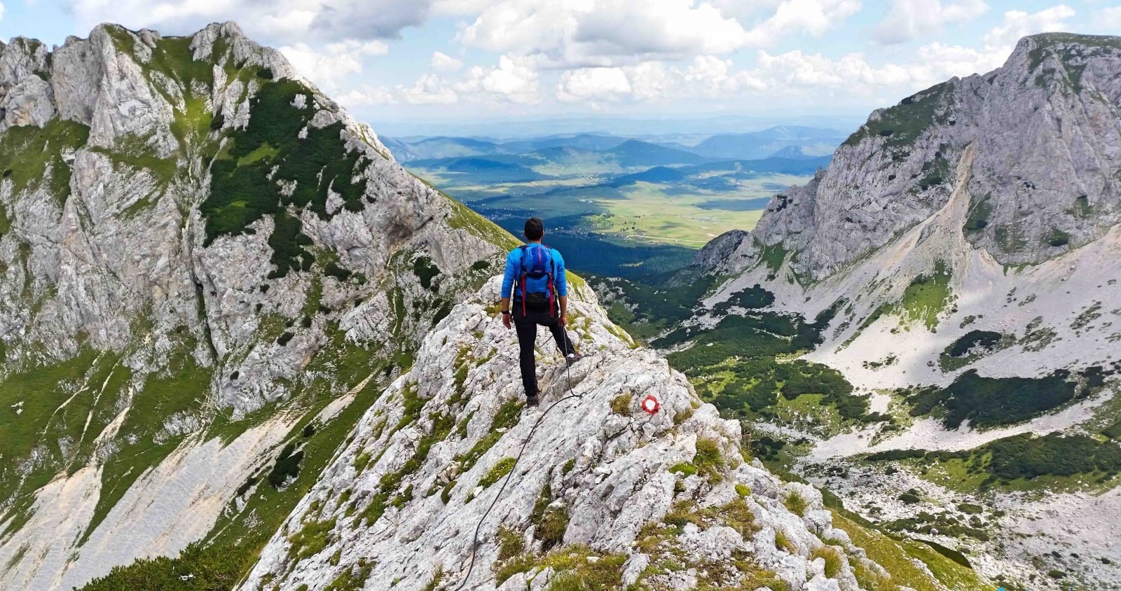 Bobotov Kuk MontenengroA hiker stands on top of a mountain rock, taking in the far-reaching views.