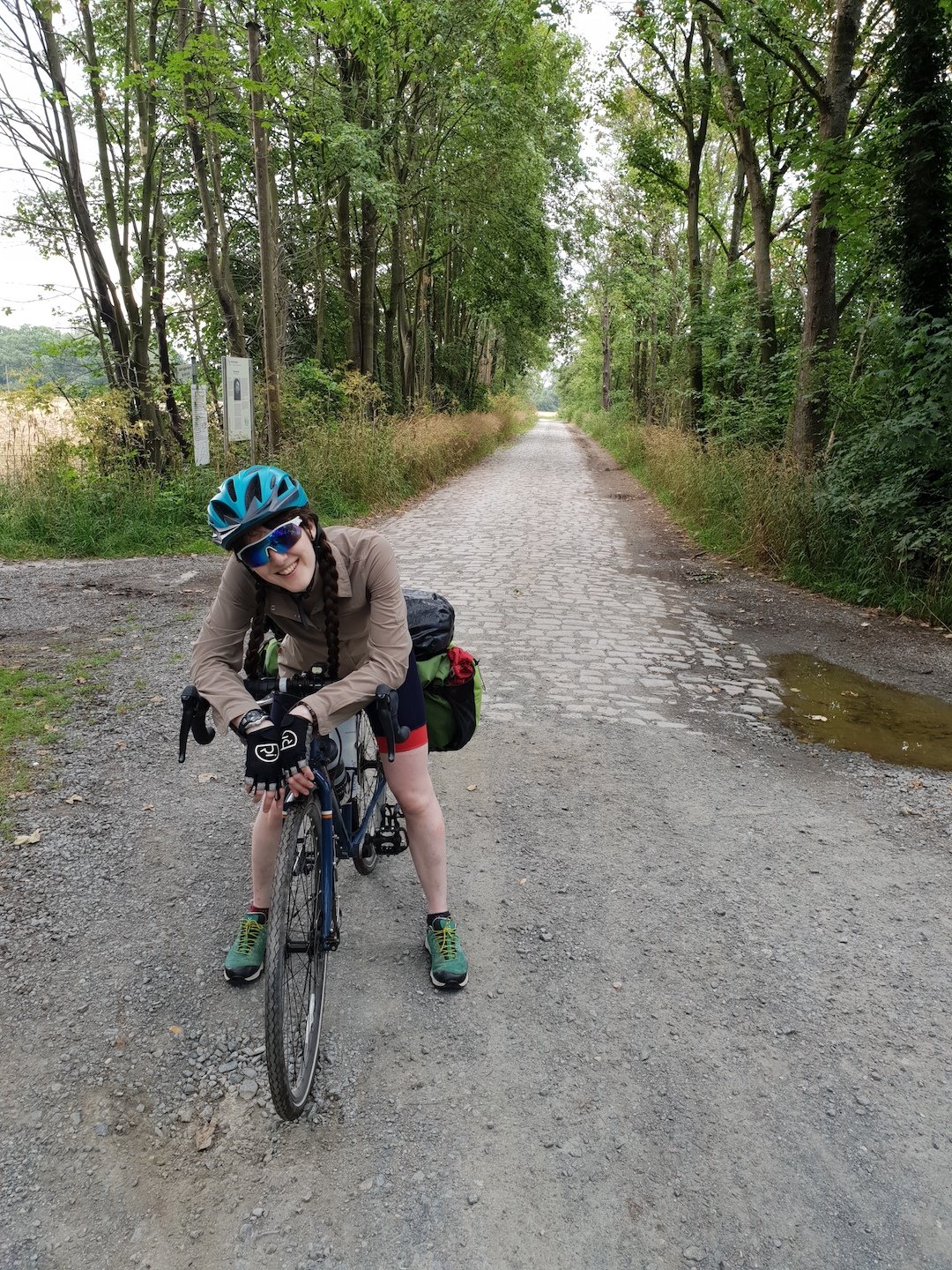 A woman posing on her bicycle, while cycling a muddy road.