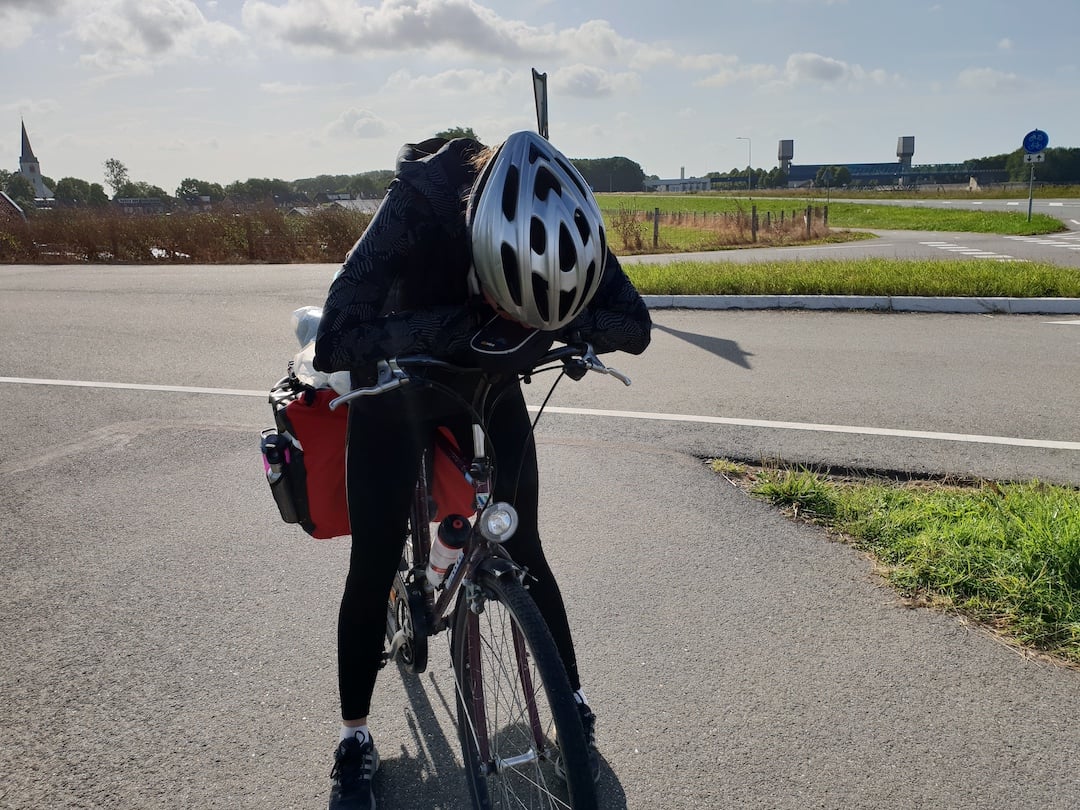 A cyclist bent over their bike, exhausted.