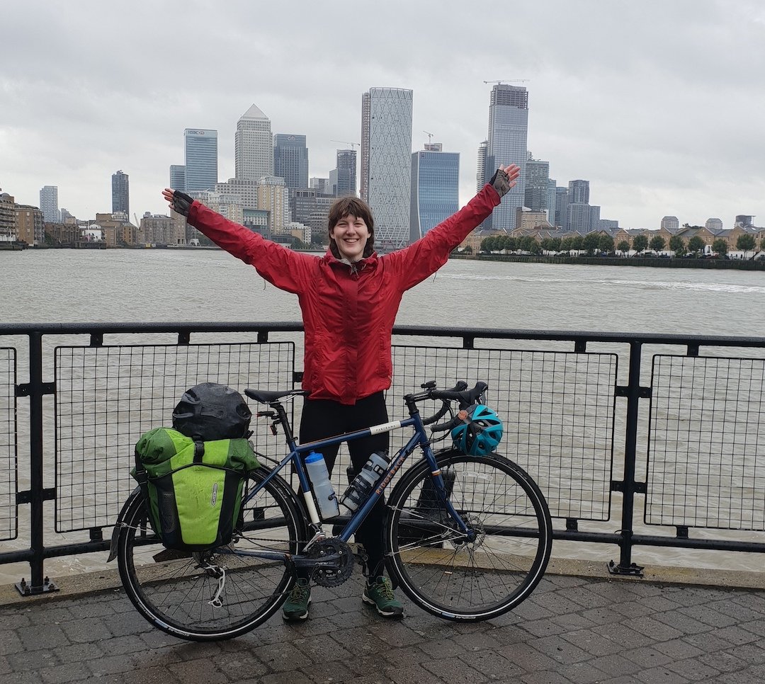 A cyclist posing in front of the buildings of Canary Wharf.