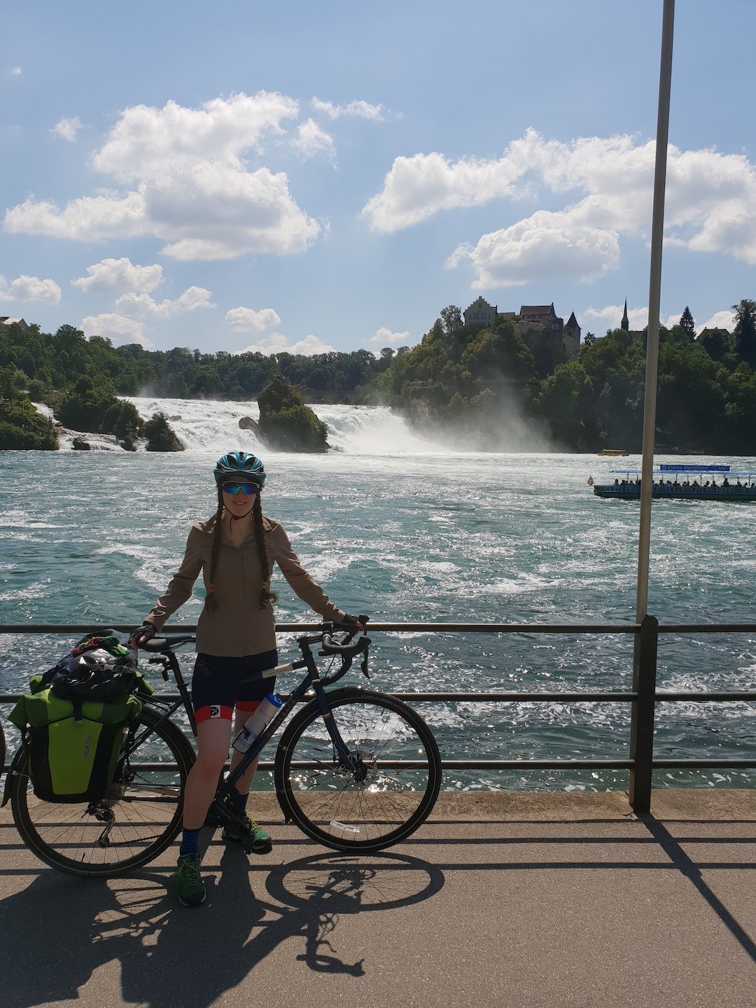 A female cyclist posing in front of the Rhine Falls.