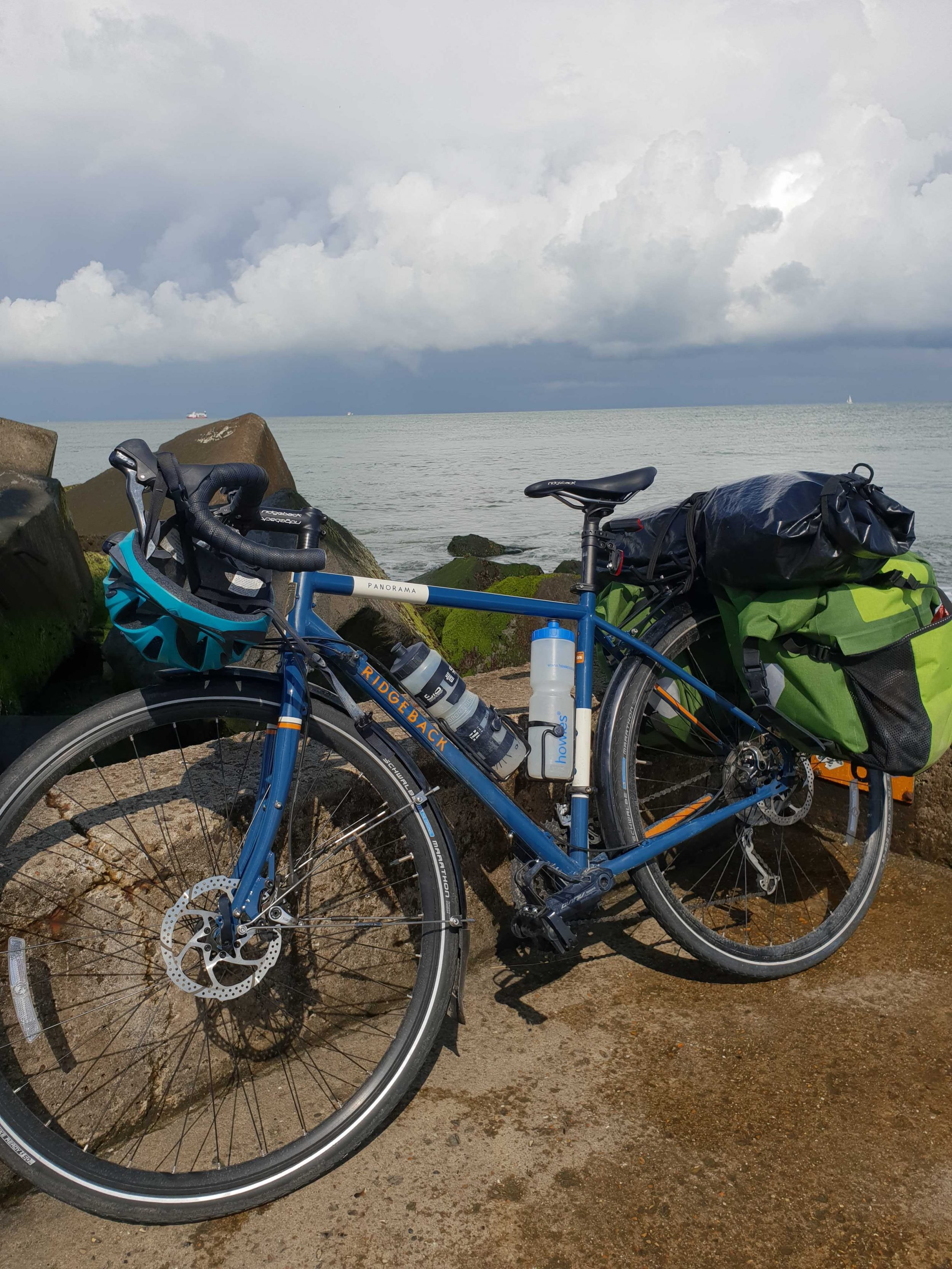 A fully packed touring bicycle, with the sea behind.