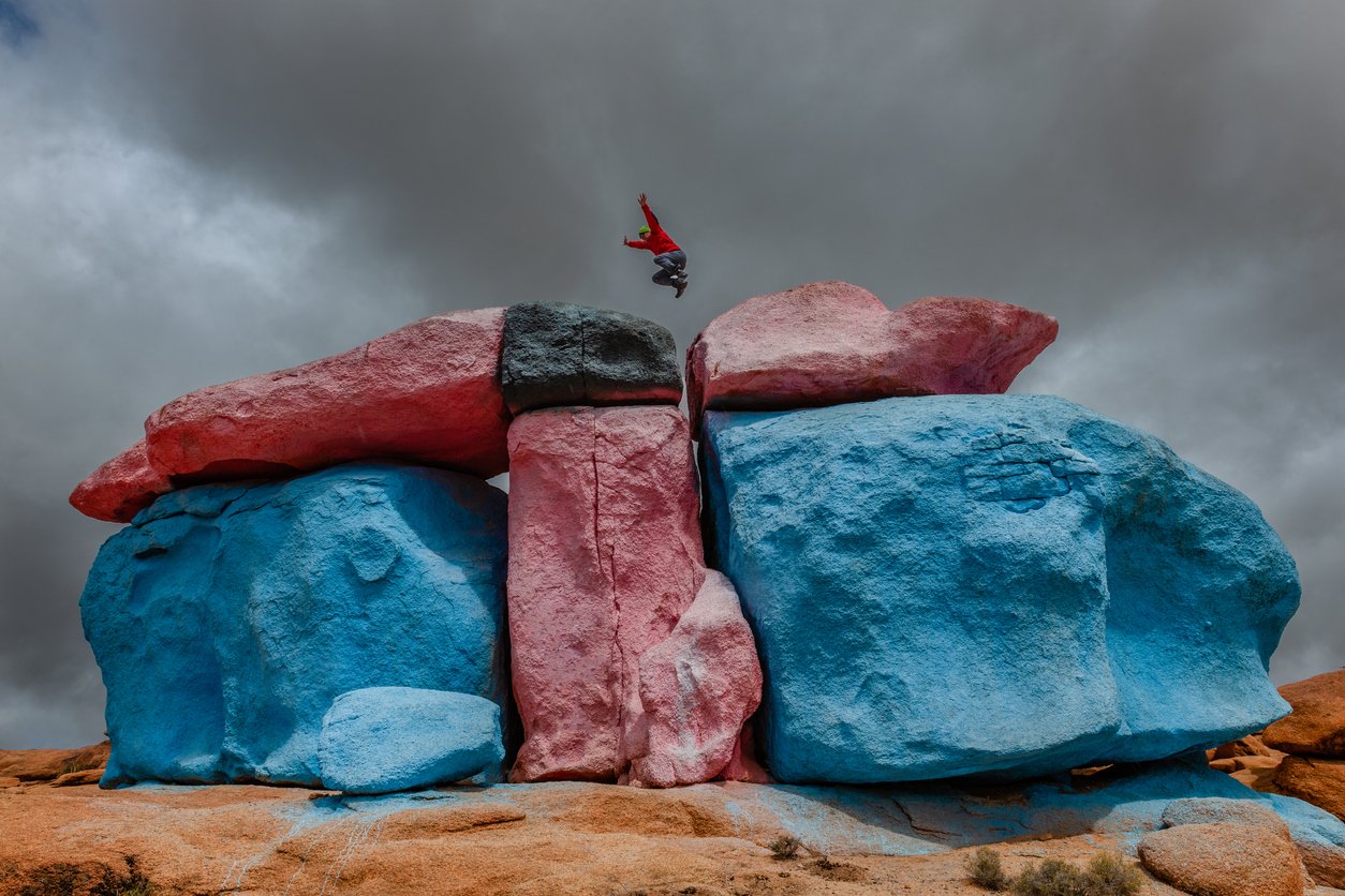 Les rochers peints des montagnes de l'Anti Atlas, avec un grimpeur sautant dessus.