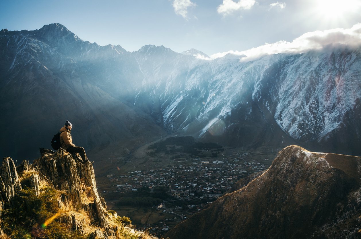 A backpacker watching sunrise over Stepantsminda in the Mtskheta-Mtianeti region