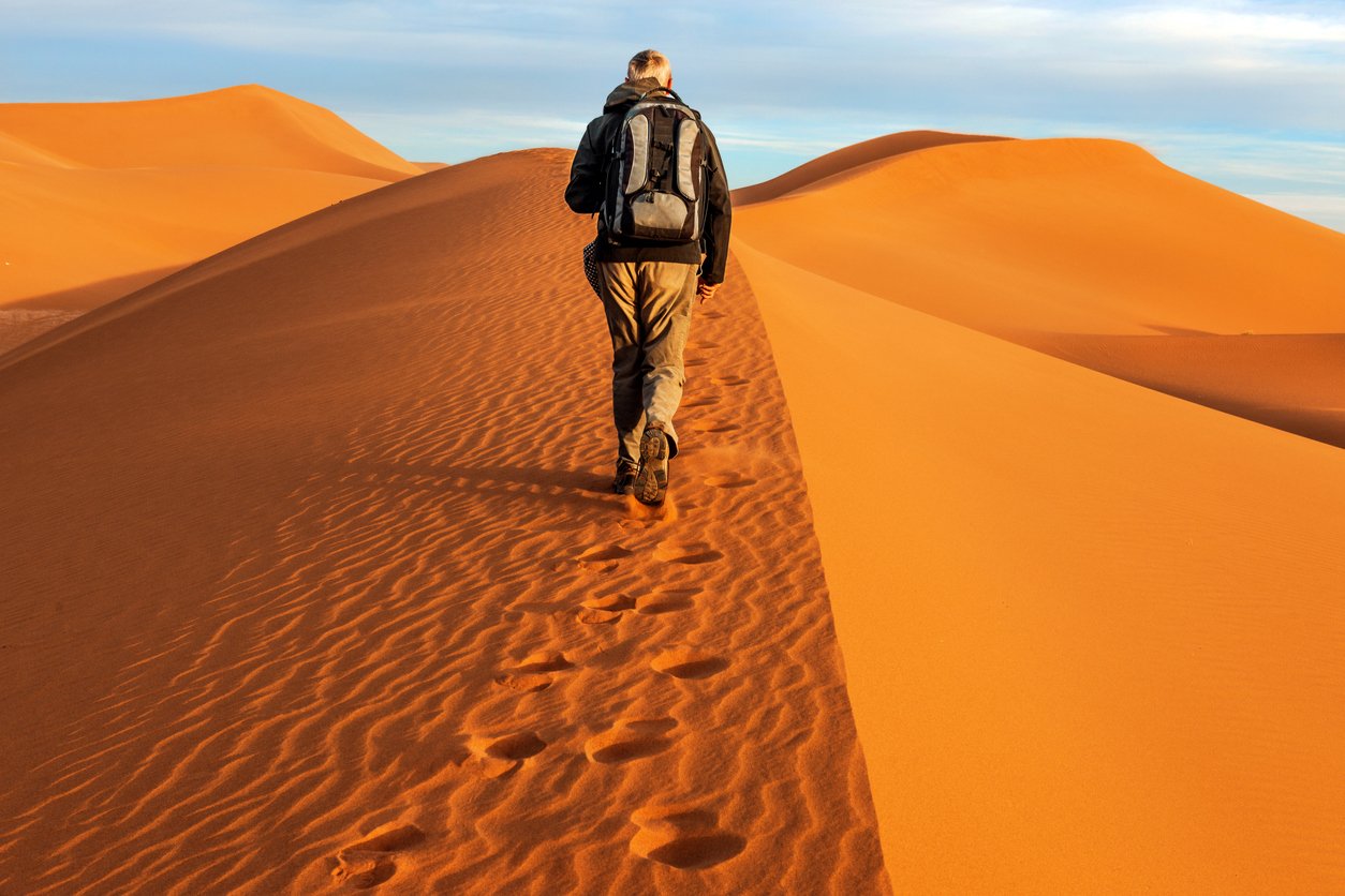A male hiker on M'Hamid dunes, in the Sahara Desert.