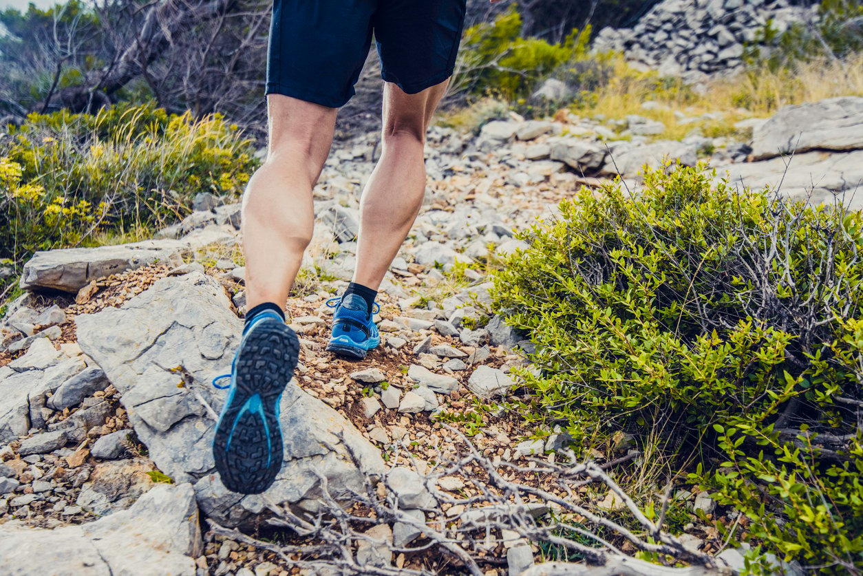 Close up of someone trail running, which shows their trainers and legs.