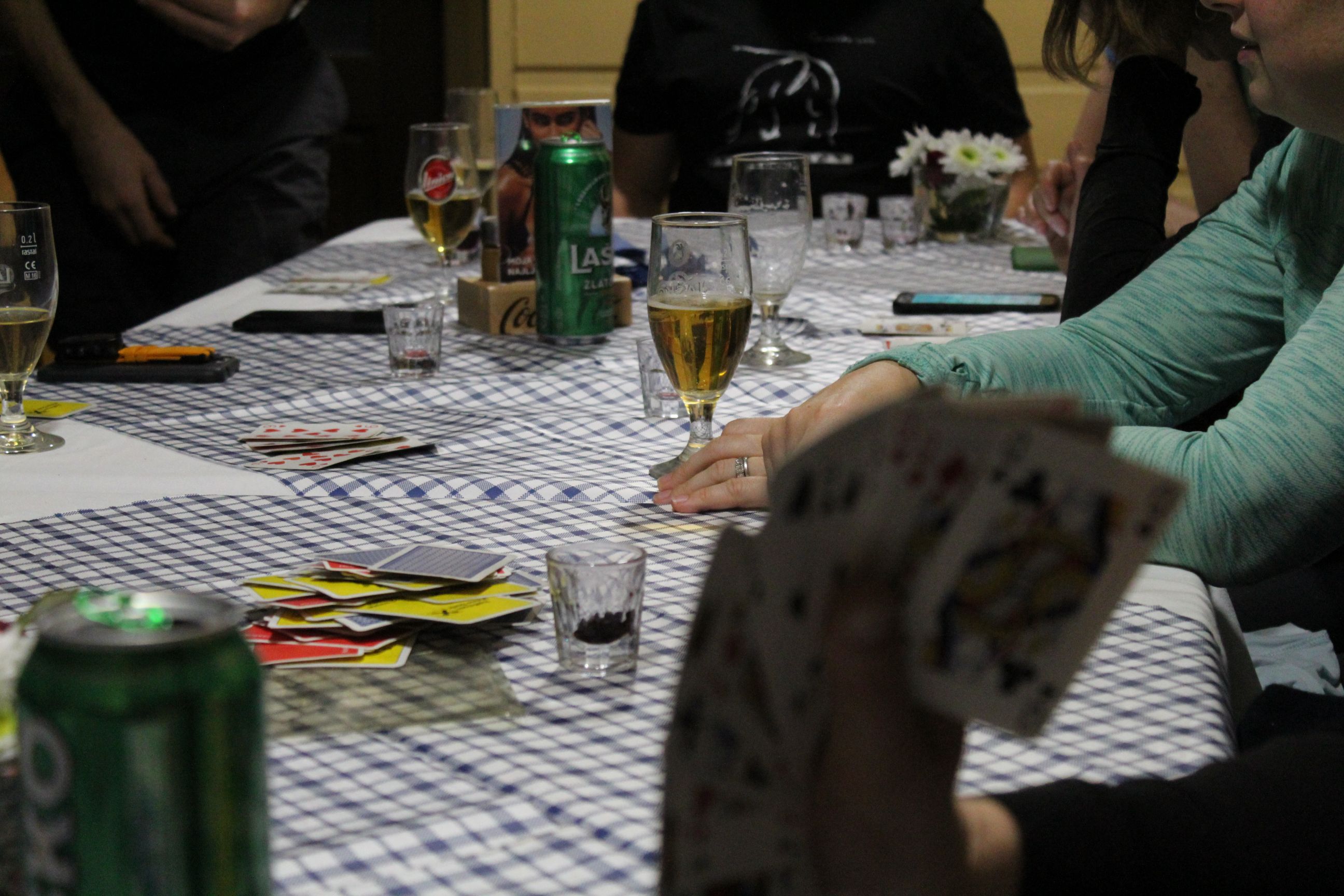 A close up of a card table in the middle of a game, with drinks balanced on it.