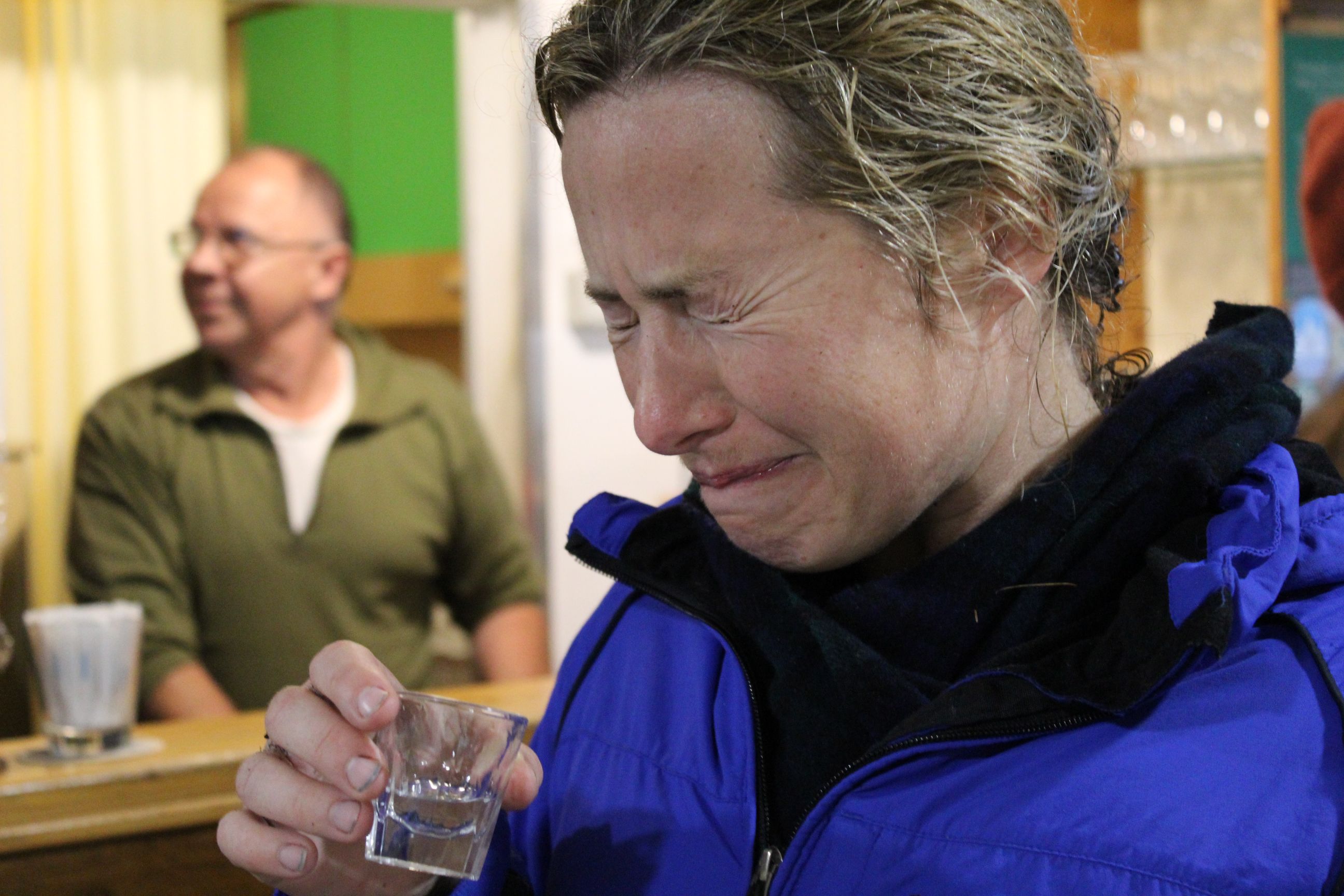 A woman wincing after downing a glass of schnapps.