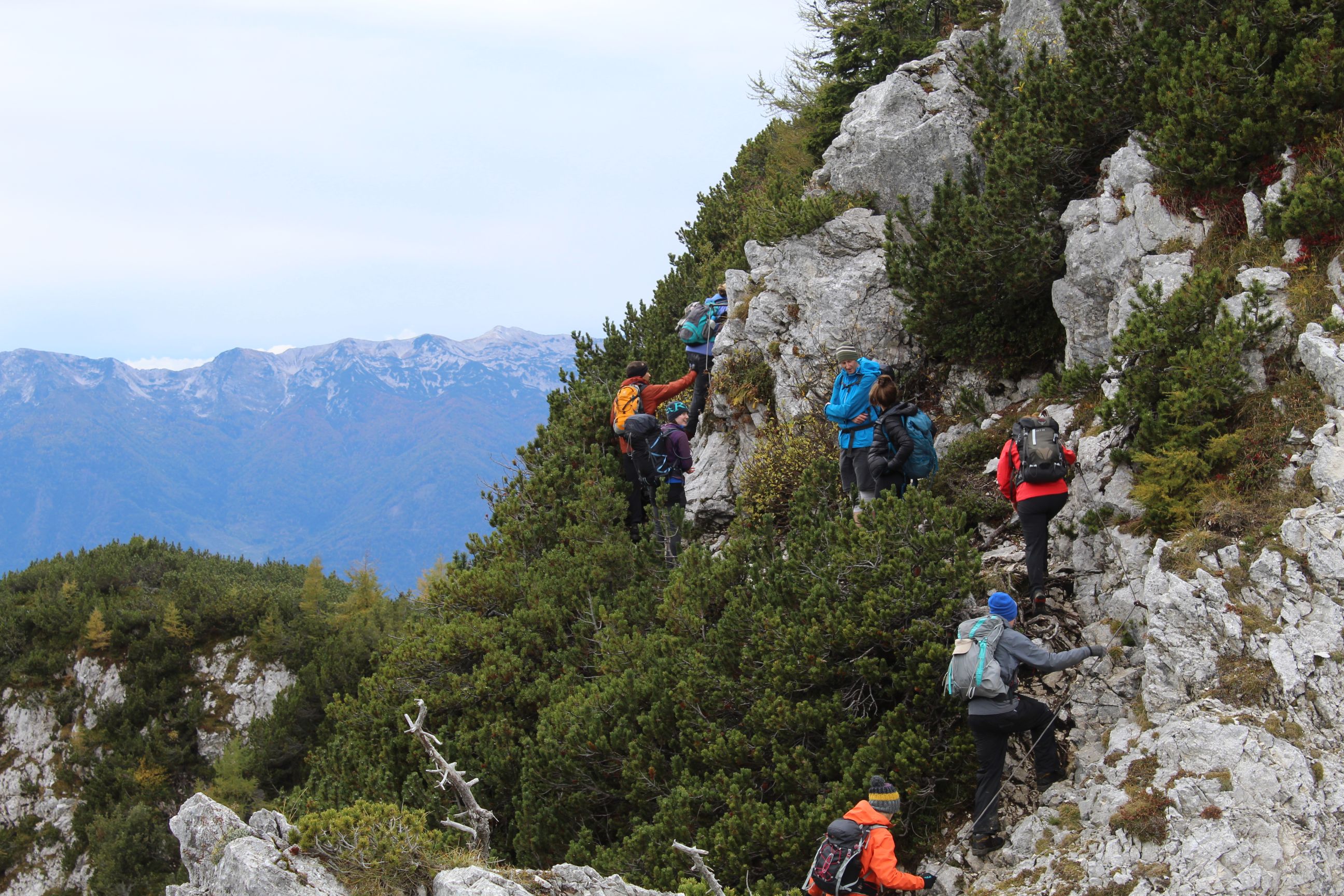 A hiking group scrambling up a rocky slope in Slovenia's Julian Alps.