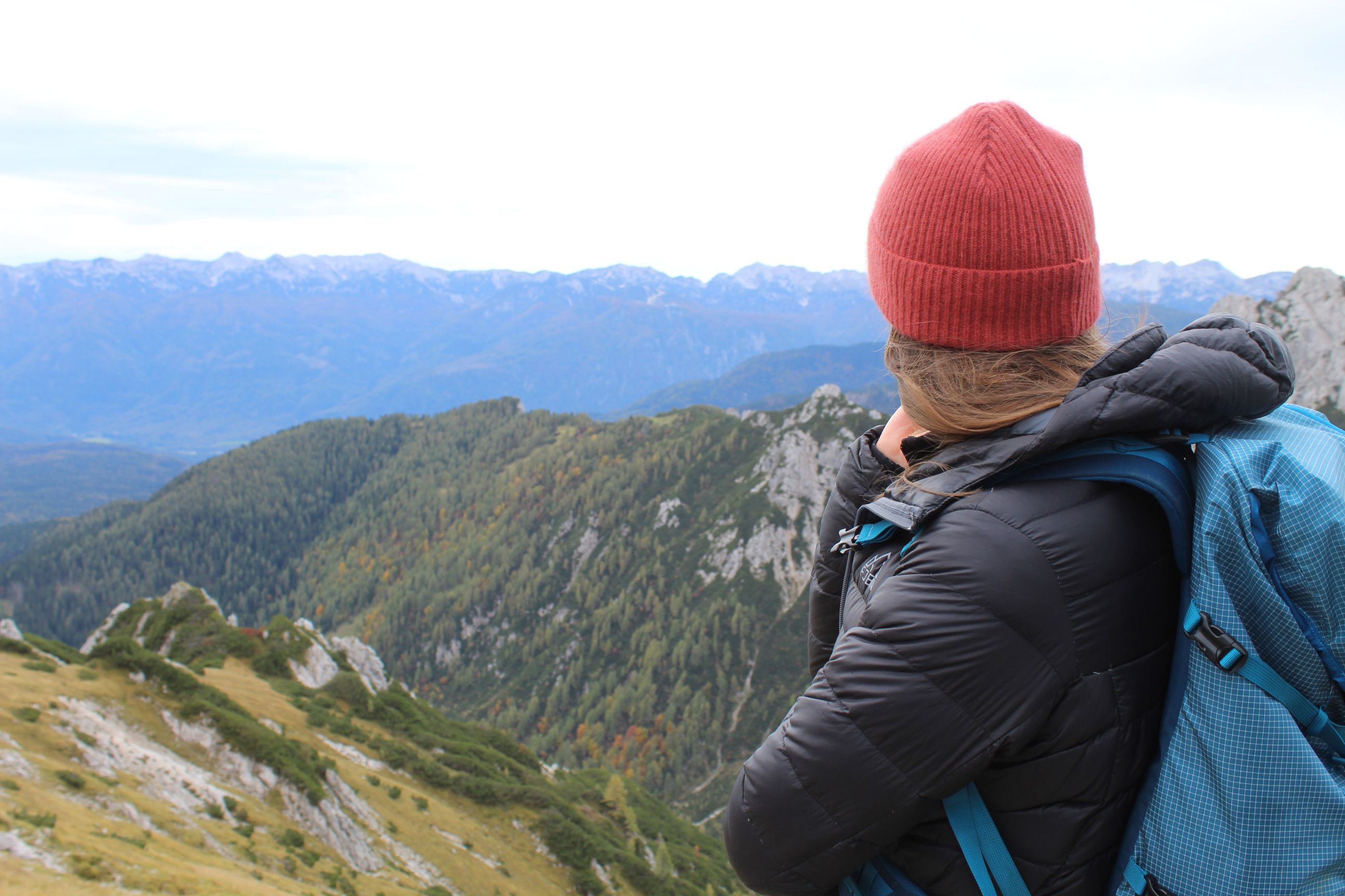 A woman hiker looking out over the forests and mountains of Slovenia.