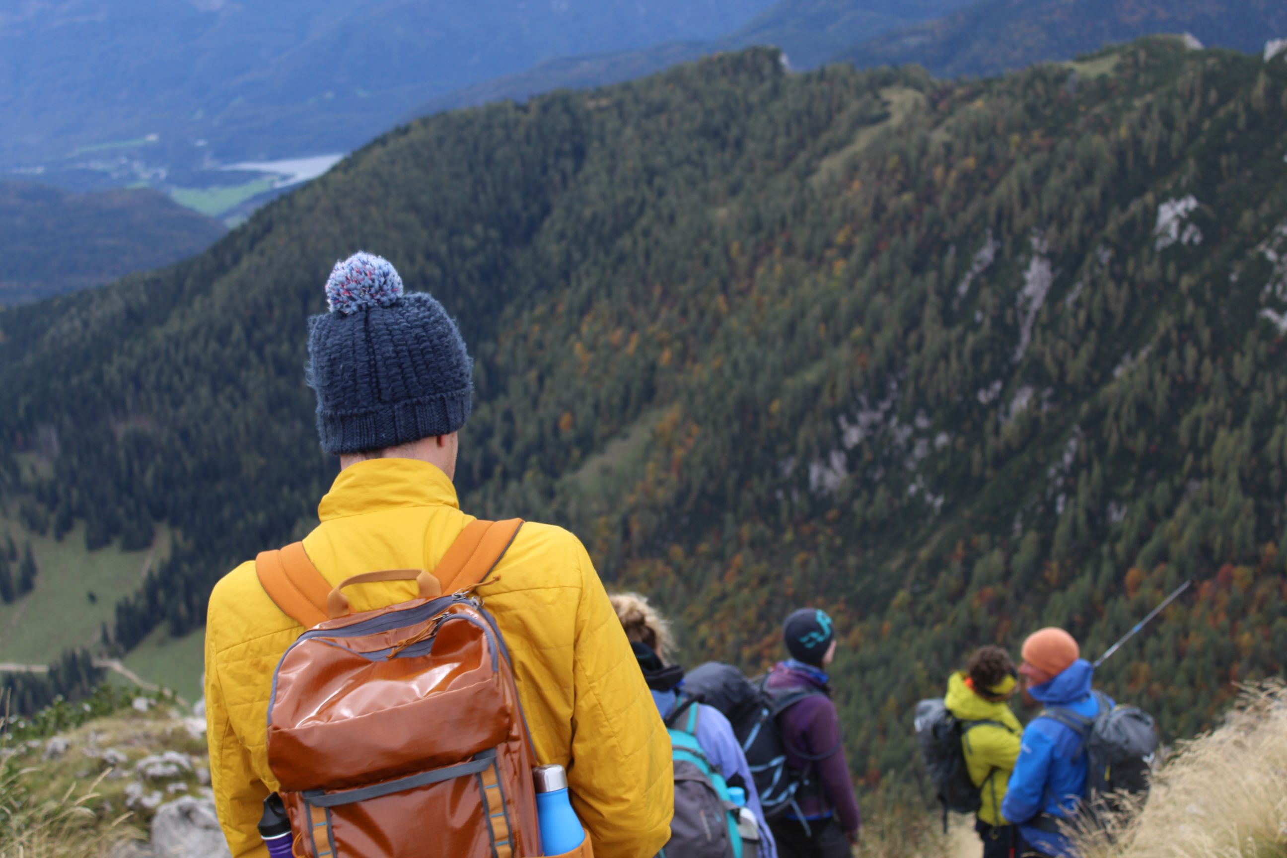Hikers descend from Mount Viševnik, a sliver of Lake Bohinj visible in the background.