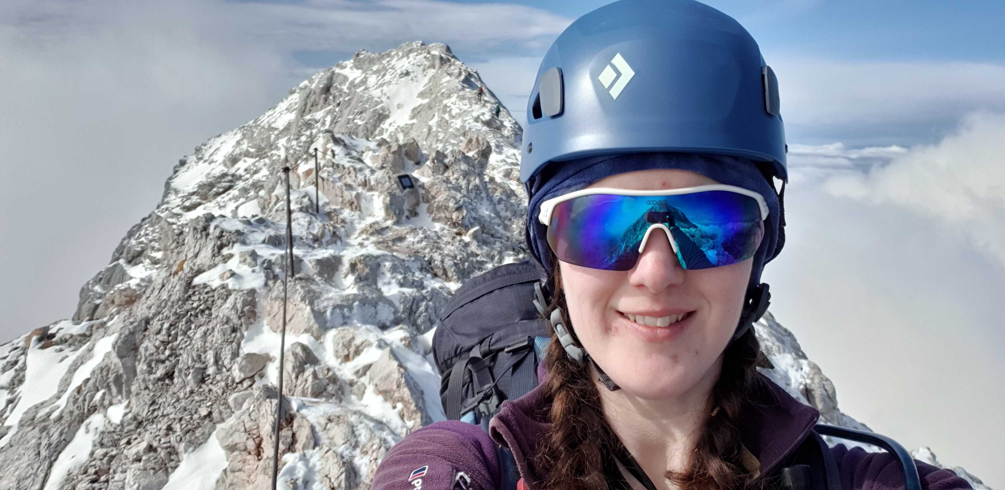 A hiker takes a selfie in front of the summit of Mount Triglav.
