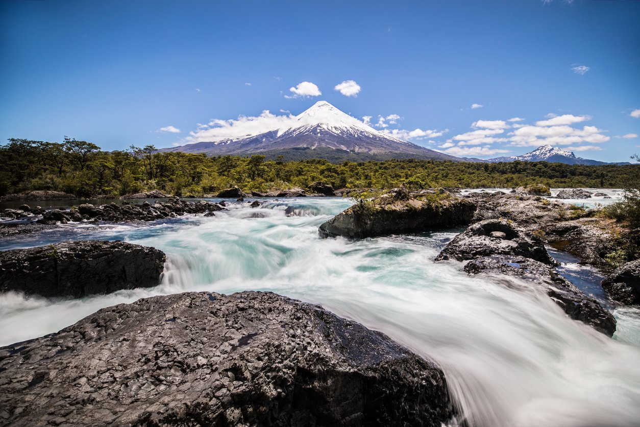 Osorno Volcano in Chilean Lake District, with a fast flowing river in the foreground.