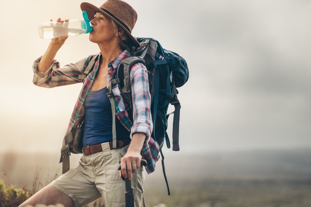 A woman hiker stops for a drink of water.